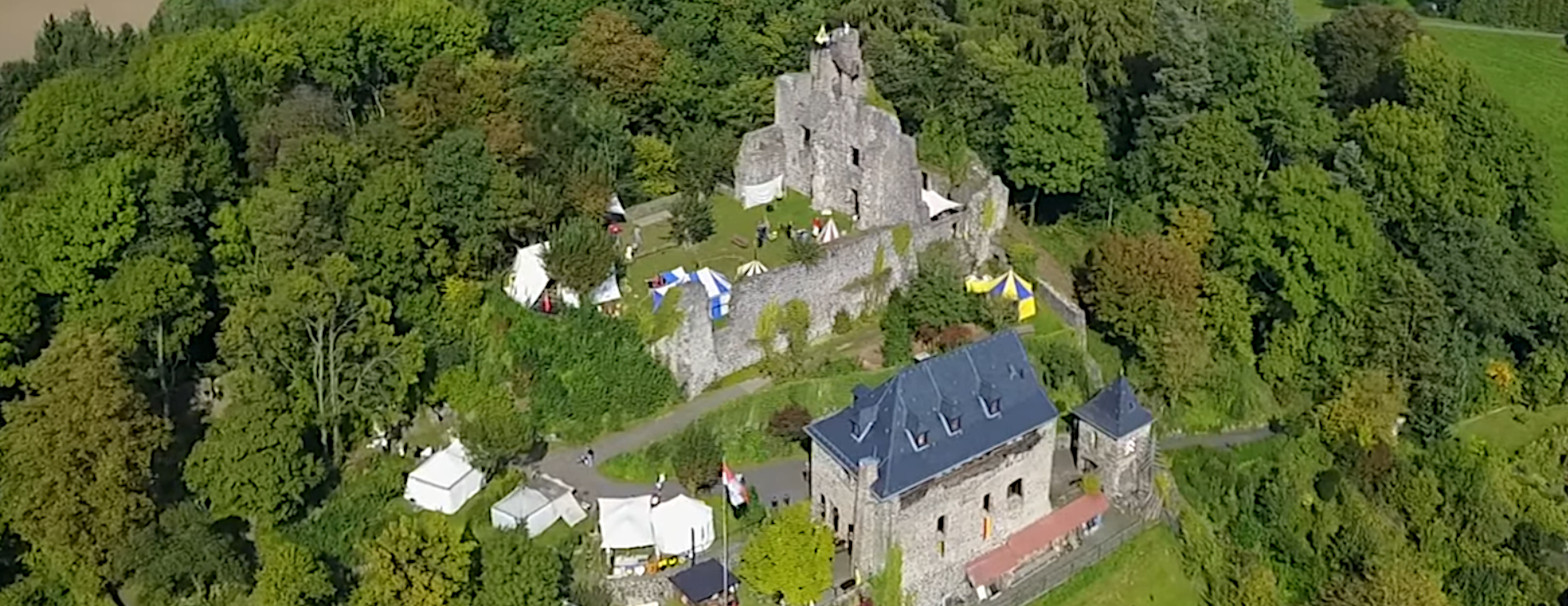 Luftaufnahme des Oberburg-Areals Staufenberg von Südwesten mit bunten Zelten einer Mittelalter-Veranstaltung. (1/3)