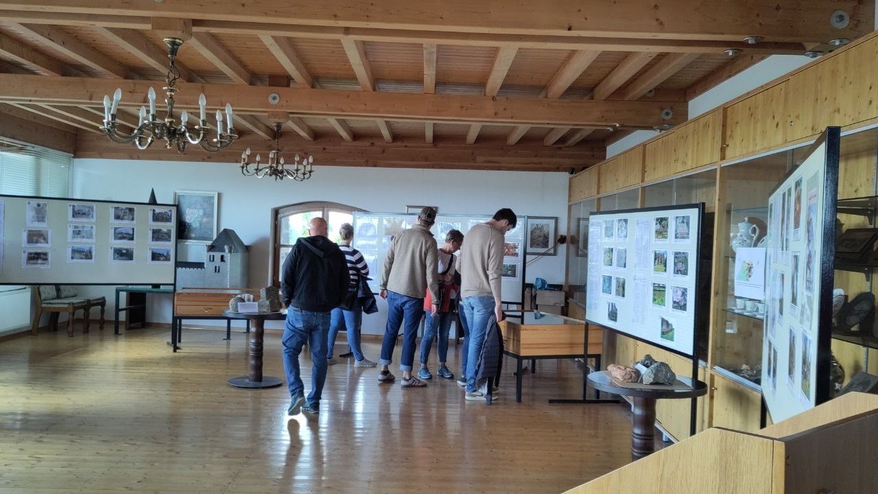 Fünf Personen in einem Ausstellungsraum mit Tischvitrinen, Stelltafeln und ausgestellten Objekten